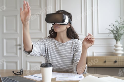 Preview: Concentrated woman bank accountant in VR headset sitting at desk at home office