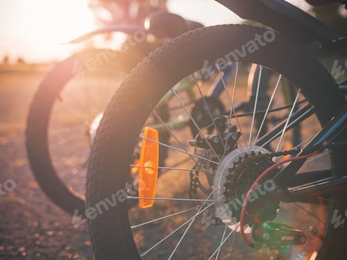 Preview: Selective closeup shot of black bicycle wheels on the background of the sunset
