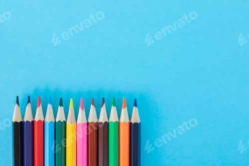 Preview: Bright colored pencils on blue paper background.