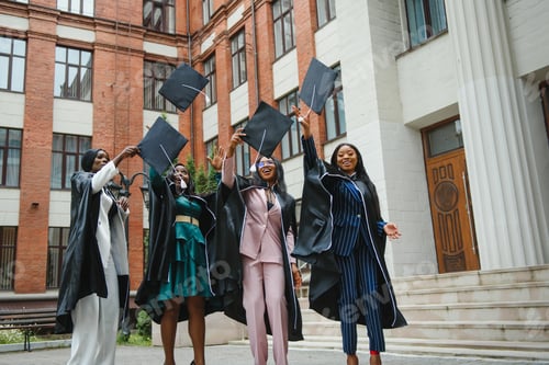 Preview: group of happy graduates throwing graduation hats in the air celebrating