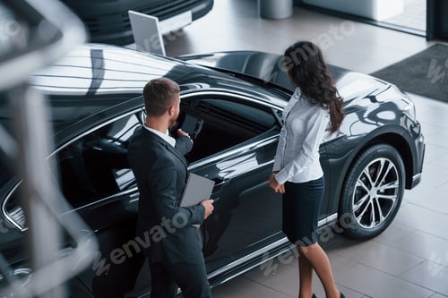 Preview: Review of the car. Female customer and modern stylish bearded businessman in the automobile saloon