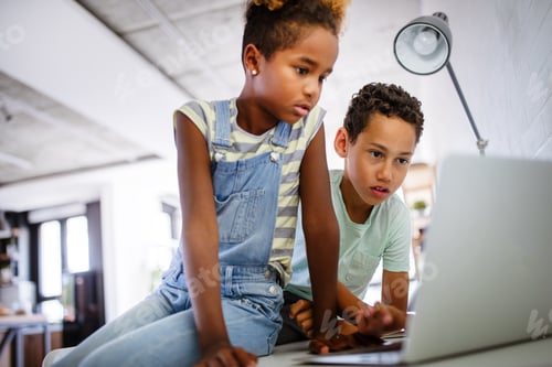 Preview: Two Focused Children Work Together on Laptop