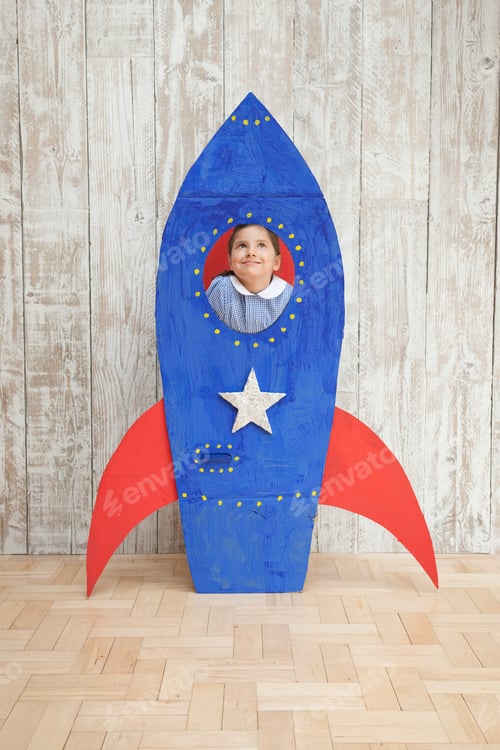 Preview: Girl looking up from window of blue homemade cardboard rocket