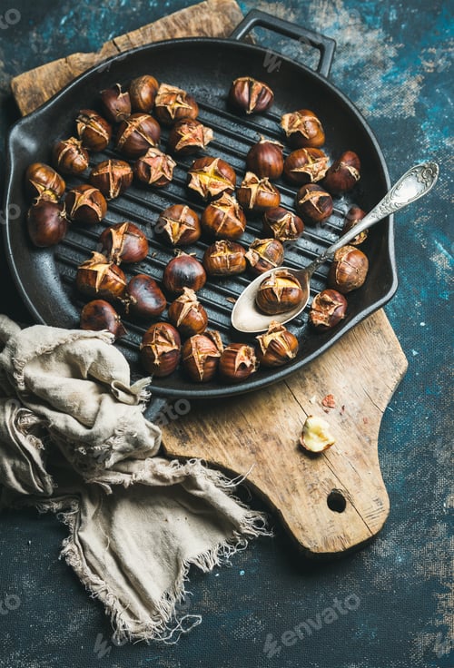 Preview: Roasted chestnuts in cast iron pan over dark blue background