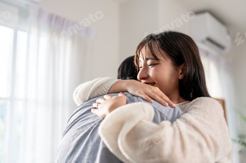 Preview: Asian young beautiful couple hugging each other in living room at home.