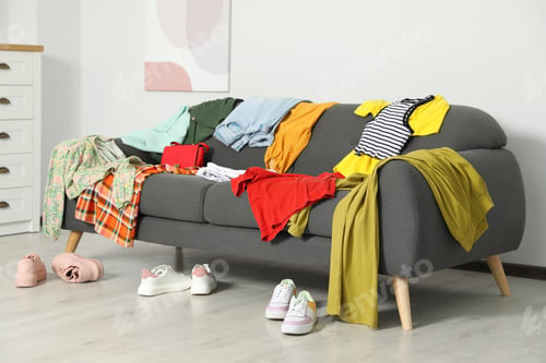 Preview: Messy pile of clothes on sofa and shoes in living room