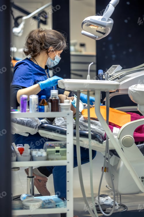 Preview: Young female dentist in dental office. Dentist at work. Dental treatment concept.