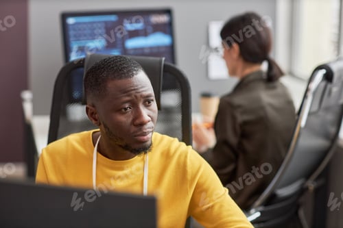 Preview: Black young man as software developer using computer at workplace in office