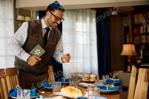 Preview: Happy man lights the menorah during Jewish festival of lights celebration.