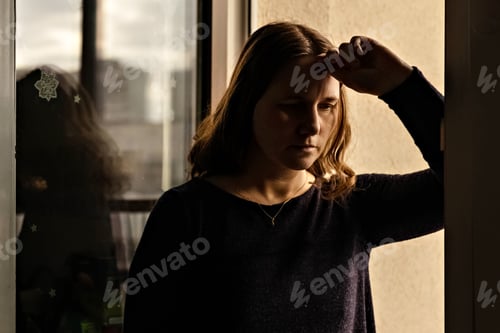 Preview: Portrait of a young woman at the window at sunset