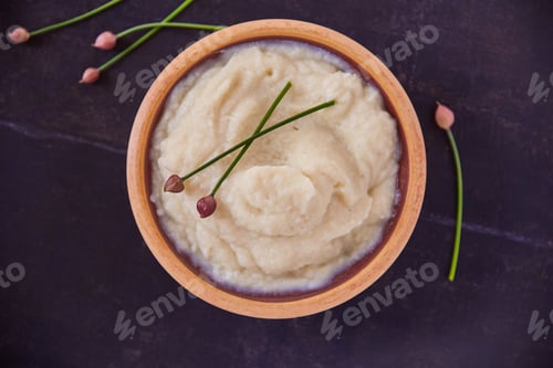 Preview: Overhead shot of cauliflower mash puree in a wooden bowl on a black table