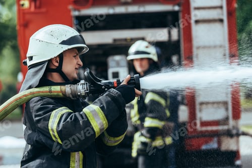 Preview: selective focus of firefighter with water hose extinguishing fire on street