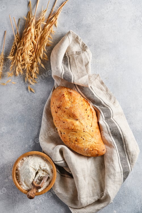 Preview: Homemade bread with seeds on light gray concrete stone table, wheat flour and ears. Top view flat la