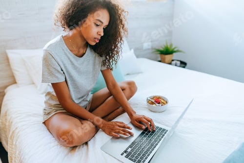 Preview: Woman writing on laptop at home