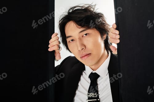 Preview: Handsome young asian man in stylish attire striking a modern pose in an urban setting