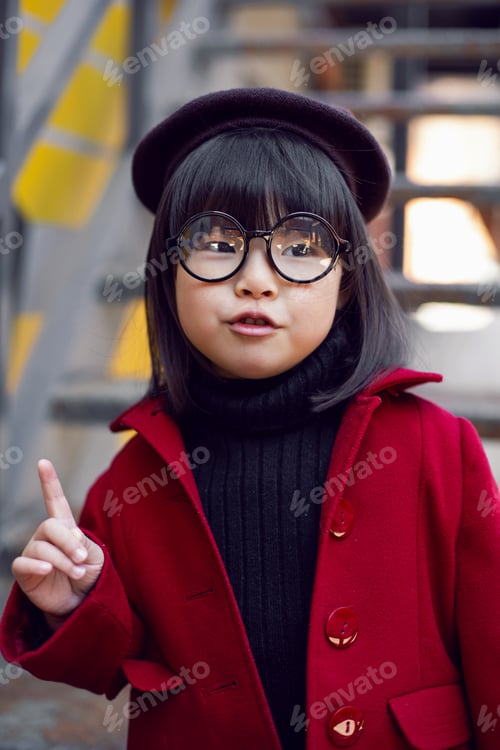 Preview: Korean girl in a red coat and cap and round glasses stands on the iron staircase the street