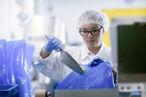 Preview: Factory worker scooping food into blue plastic bags