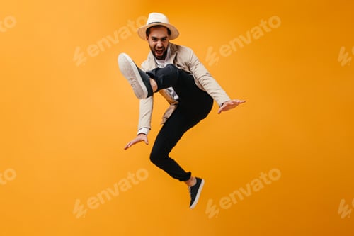 Preview: Funny man in hat jumps on orange background.