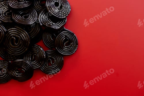 Preview: Flat lay tasty black liquorice candies on red background