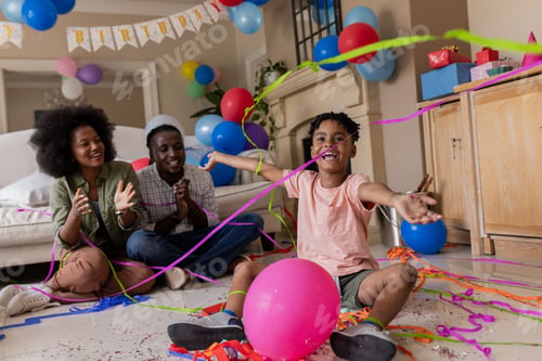 Preview: Celebrating birthday, child playing with colorful streamers and balloons at home