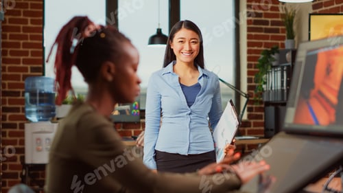 Preview: Asian woman looking at infographics notes in professional office