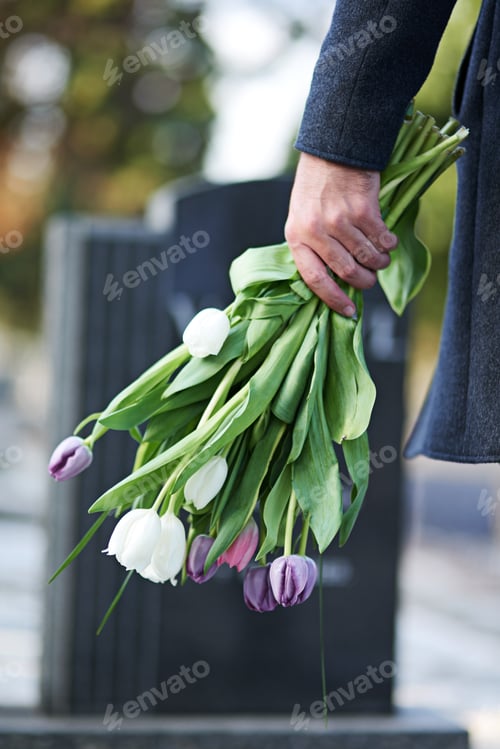 Preview: Gone but not forgotten. Cropped shot of a man visiting a gravesite with a bunch of flowers.