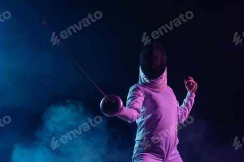 Preview: Low angle view of swordswoman fencing on black background with smoke and lighting