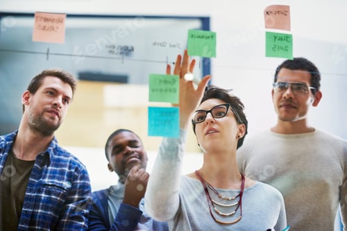 Preview: Shot of a group of designers brainstorming with notes on a glass wall in an office