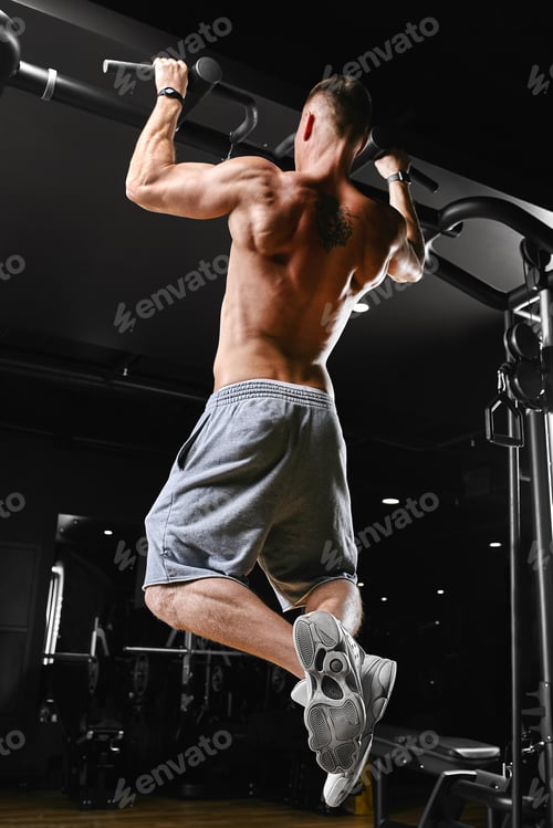 Preview: A man does pull-ups on the horizontal bar gym, a dark background, a beautiful body, Fitness