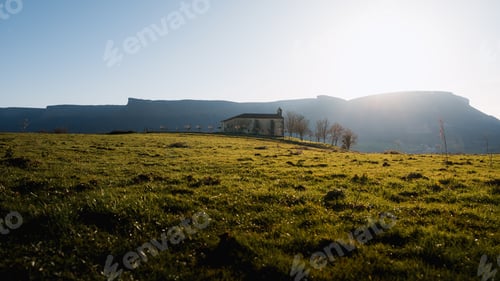 Preview: Idyllic basque countryside with chapel and majestic mountain range at sunset