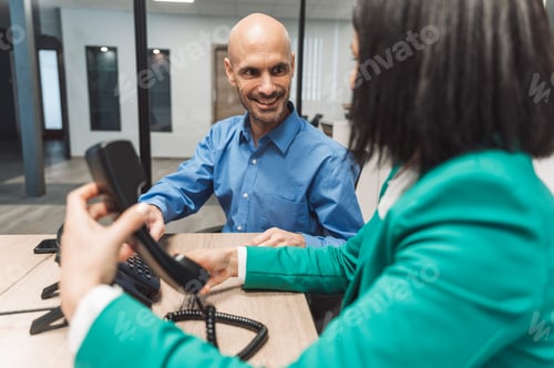 Preview: A professional interaction between two individuals in an office setting. One person, a man with a ba