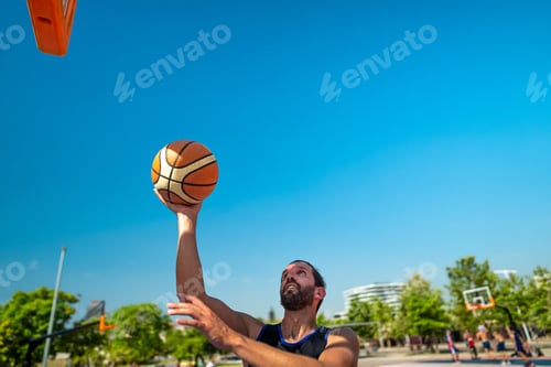 Preview: Male sportsman playing basketball throwing the ball at playground