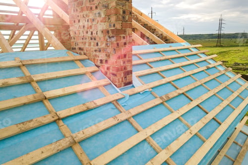Preview: Aerial view of a brick house with wooden roof frame under construction
