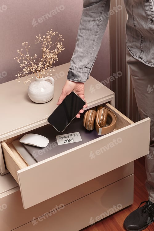 Preview: Woman putting her phone in drawer with different gadgets at home