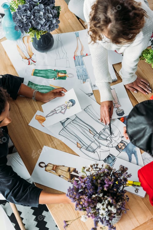 Preview: overhead view of young fashion designers working with sketches