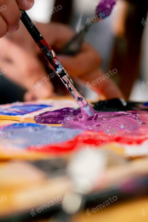 Preview: close-up in an art studio an artist mixes paint on a palette with a thin brush