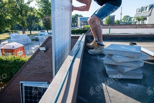 Preview: Worker stepping onto a roof while installing materials.