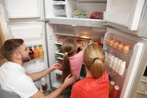 Preview: Young family choosing food in refrigerator at home