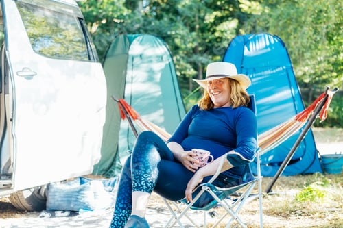 Preview: Adult woman relaxing, drinking tea while sitting in the travel chair near camper car vehicle