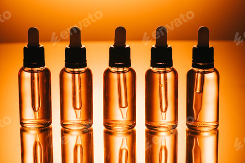 Preview: row of cbd oil in bottles with droppers on orange background