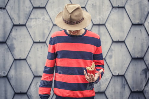 Preview: Man in stripes sweater holding small cactus.