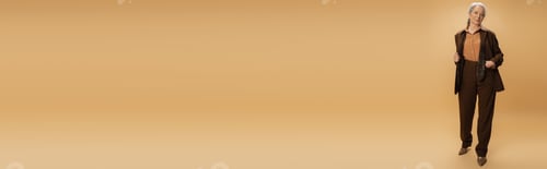 Preview: full length of senior woman in brown formal wear standing with hand in pocket on beige background,