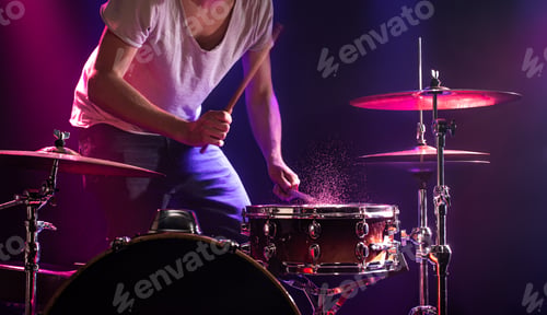 Preview: The drummer plays the drums. Beautiful blue and red background, with rays of light.