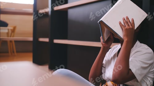 Preview: A schoolgirl is bored with reading books while preparing for exams while sitting in the library.