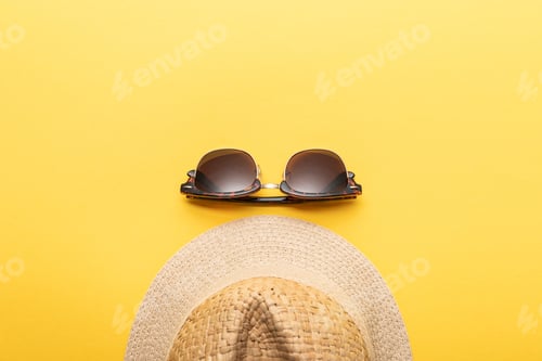 Preview: top view of straw summer hat and sunglasses on yellow background