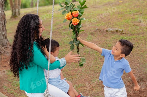 Preview: Joyful Mother on Swing Receiving Flowers from Excited Young Son