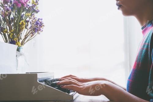 Preview: Young woman typing on a vintage typewriter