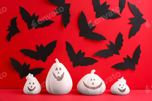 Preview: Composition with pumpkin shaped candle holders on red background. Halloween decoration