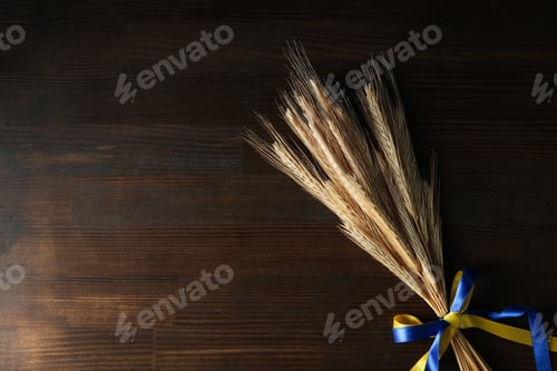 Preview: Spikelets with Ukrainian flag colors ribbons on wooden background