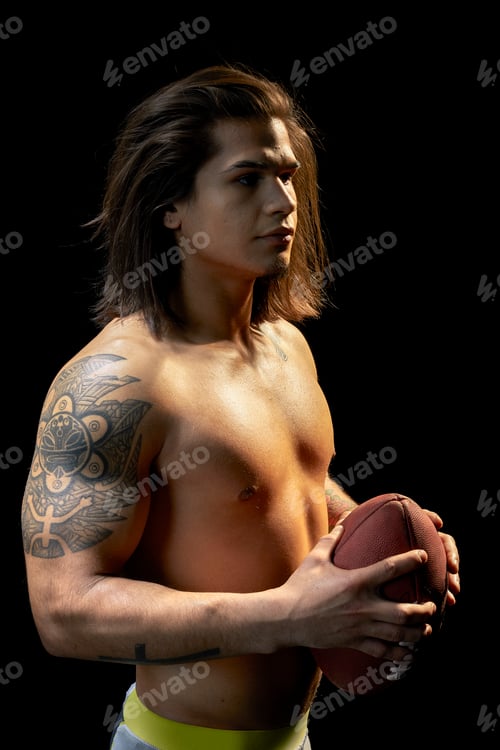 Preview: Portrait of bare chested young man with football, black background